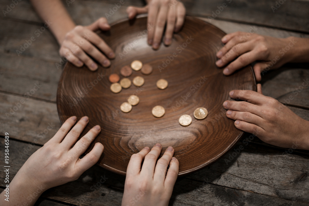 Poor people holding plate with coins on wooden background
