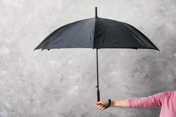 Woman holding black umbrella on grey background