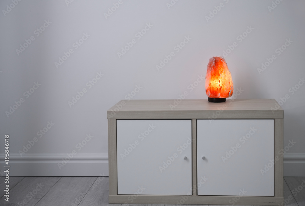 Himalayan salt lamp on wooden cabinet indoors