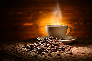 Wall Mural - Cup of coffee with smoke and coffee beans on old wooden background