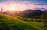 Fototapeta Zachód słońca - pink sunset over the mountains in springtime. gorgeous Carpathian countryside. beautiful rural scene with fields and trees
