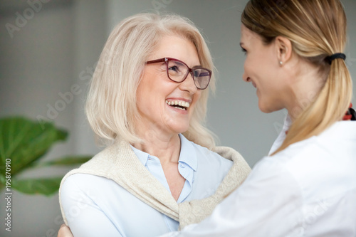 Beautiful Aged Woman In Glasses Embracing Young Adult Lady And