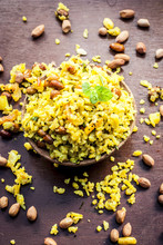 Close Up Of Indian Popular Brunch Dish In A Clay Bowl With Dried Fried Groundnut On It Is Poha Batata Or Pava Batata On A Wooden Surface In Dark Gothic Colors.