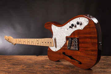 Vintage electric guitar on a wood raw table. Musical instrument. Black background with smoke