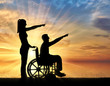 Silhouette of a disabled man in a wheelchair and his wife have a good time by the sea