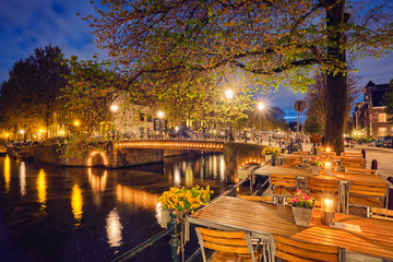 Amterdam cafe tables, canal, bridge and medieval houses in the e