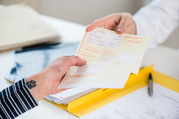 Close-up of the hand of a female patient receiving a printed medical prescription from the primary care  physician