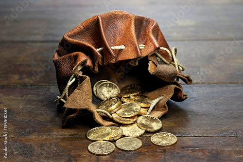 Fotomural Swiss Vreneli gold coins in a leather purse on rustic wooden background