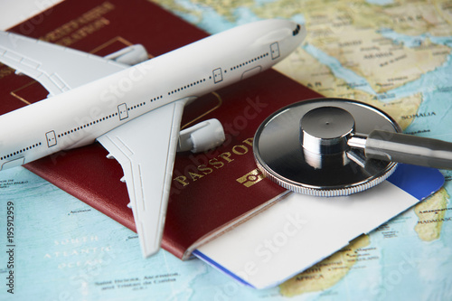 Fotografía Boarding pass and a passport travel documents with medical stethoscope and airplane on world map background, close-up