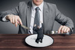 Businessman holding fork with knife and ready to eat small scared businessman on the plate. Hungry businessman ready to eating a competitor