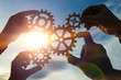 © gerasimov174 - Silhouettes four hands collect the gear from the gears of the details of the puzzles. against the background of sunlight. Concept business idea. Teamwork. strategy, cooperation. Close-up