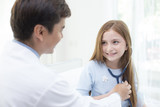 Fototapeta  - Doctor teaching girl how to use stethoscope with attractive smiling.
