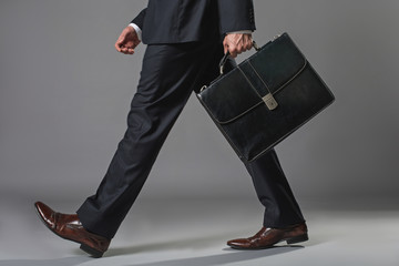 Low angle close up of male legs. Man walking in business suit with suitcase