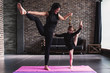 © undrey - Happy mother and daughter wearing black sportswear having fun while doing leg stretching exercise standing on one leg at home