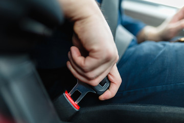 men's hand fastens the seat belt of the car. close your car seat belt while sitting inside the car b