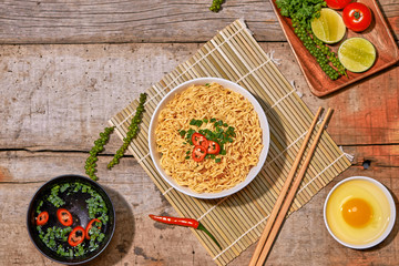 instant noodles in bowl with vegetable on wooden table.