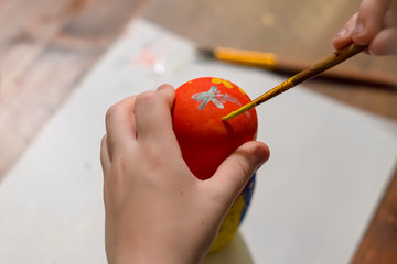 Wall Mural - little boy paints russian nesting doll called matrioshka with red and yellow paint