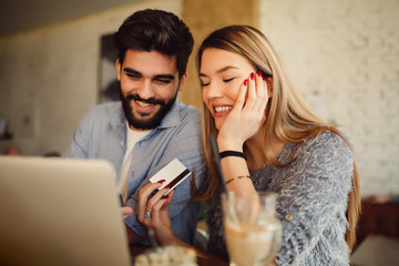 Wall Mural - Young couple in love enjoying time spending with each other in cafe and shopping online.