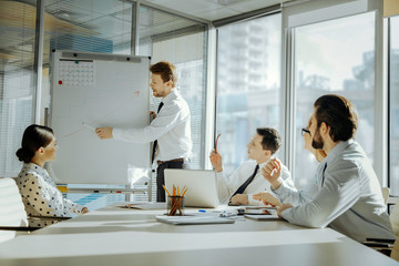 Wall Mural - Way to success. Charming young boss telling his colleagues the requirements for the progress of the project implementation, pointing at the graph on the whiteboard