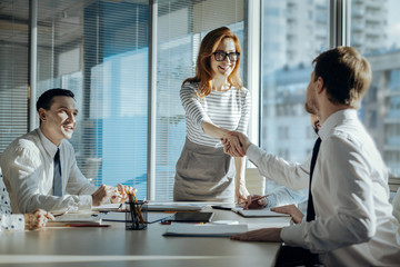 Best cooperation. Charming young woman carrying out a meeting with her companys business partners and shaking hands with a new one