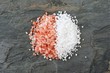 Pile of half pink Himalayan and half sea salt. Top view on a dark background. Comparison concept.