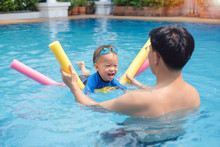 Cute Little Asian 18 Months / 1 Year Old Toddler Boy Child Wear Swimming Goggles Learning To Swim With Pool Noodle At Outdoor Pool; Dad And Son Relaxing In Swimming Pool Of Clubhouse In Summer Day