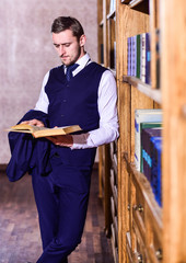 Leinwandbilder - Student reads book near bookshelves, defocused. Student or intelligent man