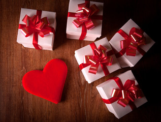 Wall Mural - white festive gift boxes with red bows on a wooden table with red heart