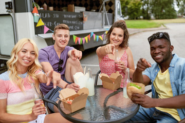 Canvas Print - happy friends with drinks eating at food truck