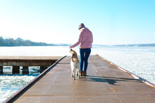 Woman Walking Cute Dog Outdoors On Winter Day. Friendship Between Pet And Owner