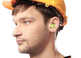 Wall Mural - Male worker with earplug on white background. Hearing protection equipment