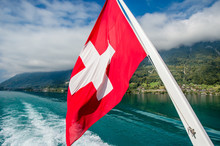 Red Swiss Flag Over Alps Of Lake Brienz In Interlaken, Switzerland.