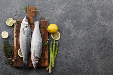 Poster - Fresh raw seabass on cutting board with ingredients. Top view, copyspace.