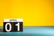 April 1st. Day 1 of april month, calendar on table with yellow background. Spring time, empty space for text