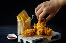 Female Hand Touching Fried Chicken Breasts. Junk Food Concept. Black Background