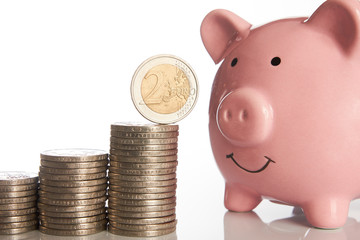 Wall Mural - Pink piggy bank and stack of coins growing up with two euro coin on white background, business investment or saving concept