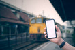 Hand man holding smartphone with blank white screen on blur image of bus train station  background