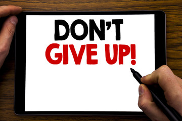 Handwriting Announcement text showing Don t Give Up. Business concept for Motivation Determination, Written on tablet laptop, wooden background with businessman hand, finger writing on PC.