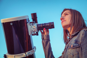 Wall Mural - cute young woman holding astronomical telescope and looking at the sky.