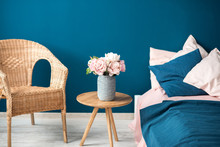 Cozy Bedroom Fragment Of Interior With Flowers Bed And Chair On The Blue Wall Background