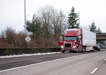 Road patrol Police inspects stopped long-haul big rig semi truck with reefer trailer stopped on winter highway