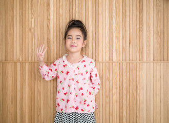 Portrait of happy little girl , wood background, show four fingers