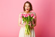 © LIGHTFIELD STUDIOS - portrait of surprised woman looking at bouquet of pink tulips in hands isolated on pink