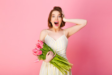 Wall Mural - portrait of excited woman with bouquet of pink tulips isolated on pink