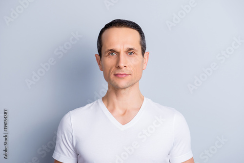 Fotomural Portrait of trendy, neat, shaven, brunet man in white t-shirt with serious expre