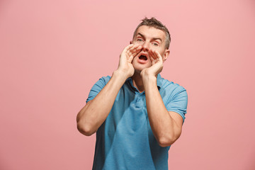 Wall Mural - Isolated on pink young casual man shouting at studio