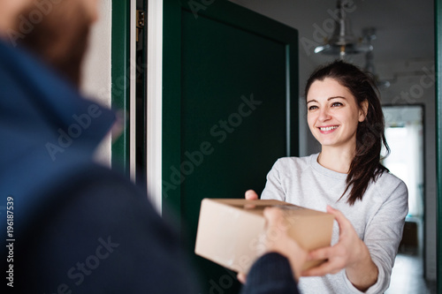 Fotomural Woman receiving parcel from delivery man at the door.