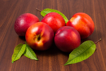 Wall Mural - Peaches with leaves on a dark wooden table