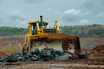 A yellow bulldozer builds a road in an iron ore quarry.