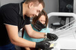 © anatoliy_gleb - Dentist explains something to a smiling female patient with a rubberdam on her head